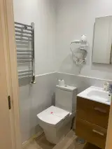 Interior Apartment bathroom seen from the doorway with toilet, chrome towel rail, hairdryer and basin